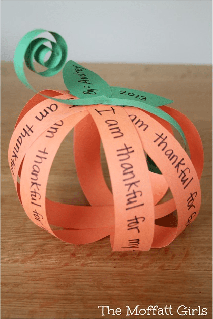 A pumpkin made from orange strips of paper, each with something the maker is grateful for written on it