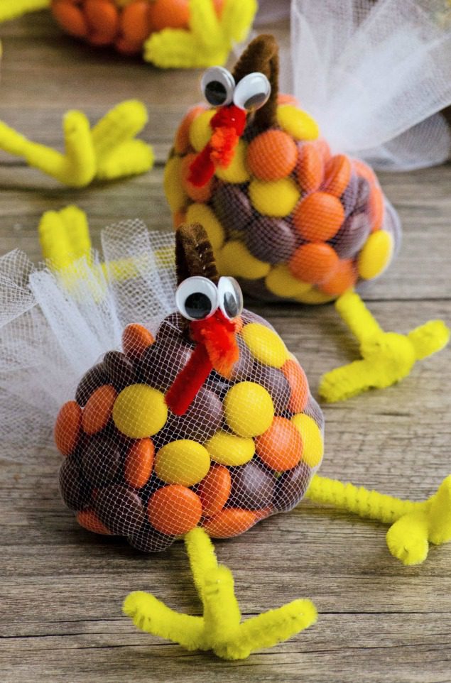 A netted bag embellished to look like a turkey is filled with fall colored candies