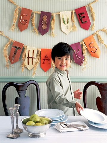 A boy stands in front of a banner that reads Give Thanks