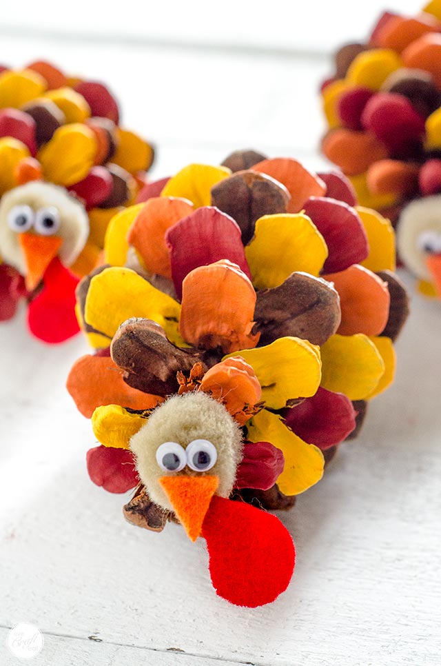 A pinecone turkey with each of the sections of the pinecone painted a different color 