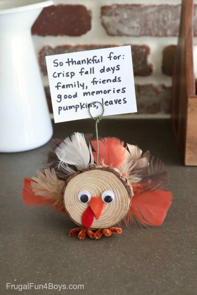 A turkey photo holder made from a small slice of wood decorated with googly eyes and feathers