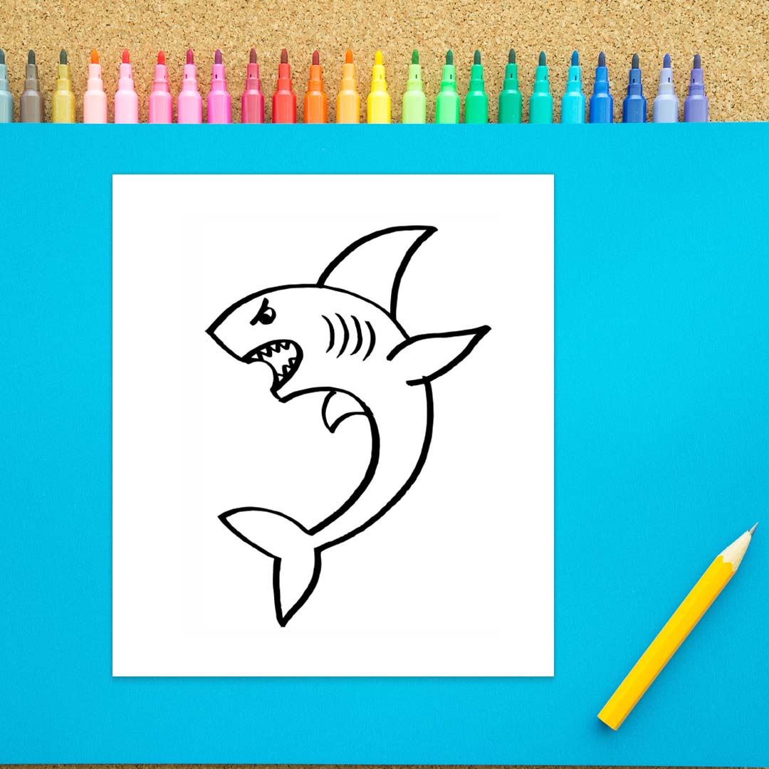 An angry looking shark is drawn in black marker on a white background. There are several fins, a tail, and a face drawn. 