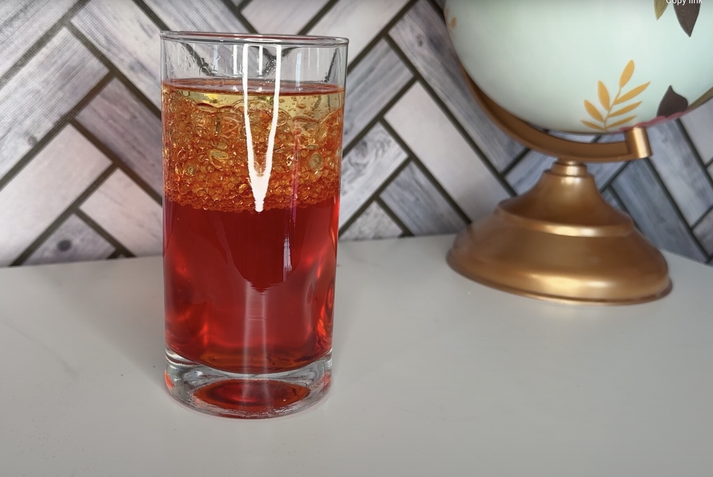 Adding oil to colored glass of water