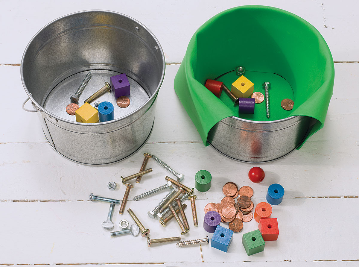 Two tin buckets hold a variety of objects as an example of kindergarten science experiments