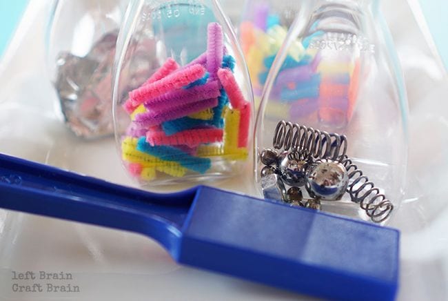 Plastic bottles filled with pipe cleaners and metal springs with a large blue mar magnet (Kindergarten Science)