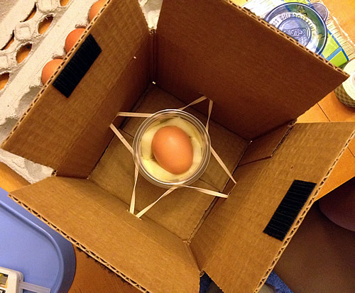 egg in a box with a jar and rubber bands for an egg drop idea