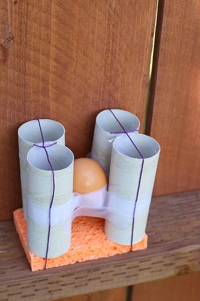 egg held in place on a sponge with toilet paper rolls and rubber bands and tape
