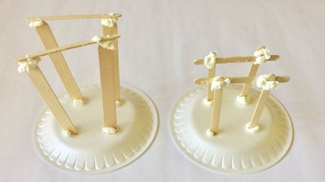 Two foam plates with structures built from wood craft sticks and putty on top in this example of 6th grade science fair projects