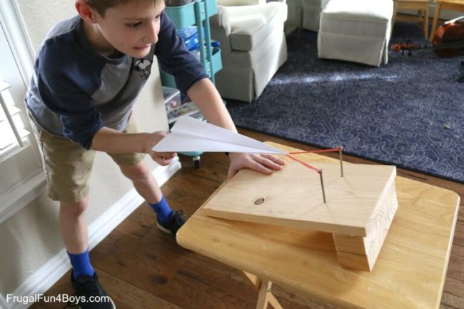 Sixth grade science student using a homemade launcher to launch a paper airplane in this example of 6th grade science fair projects.