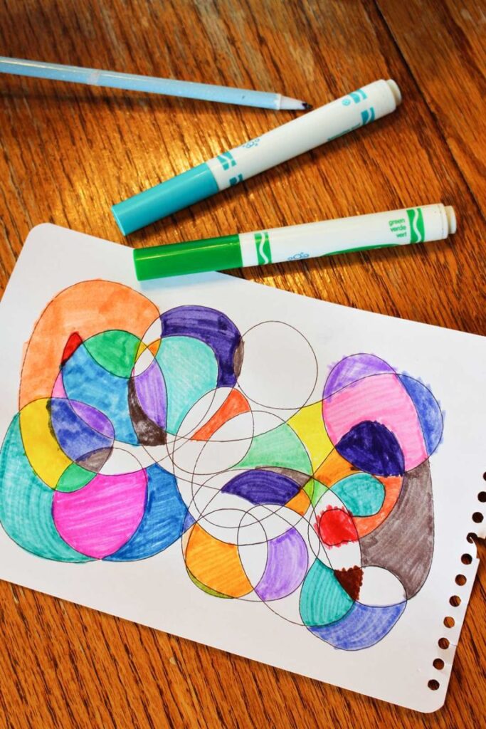 A piece of paper has intertwining circles that are colored with markers - example of directed drawing activities