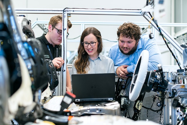 Three mechanical engineers look at a laptop while surrounded by mechanical equipment