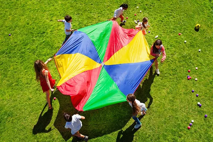 Students stand around a brightly colored parachute as an example of elementary PE games