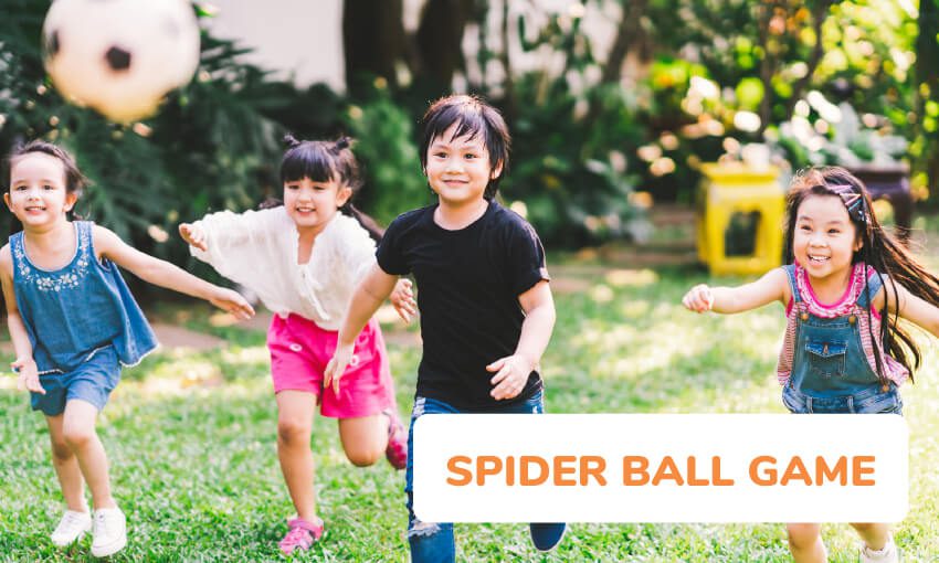 Four children facing the camera are chasing after a soccer ball flying through the air as an example of elementary PE games