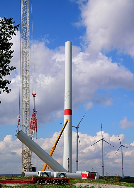 A wind turbine in the midst of construction stands against a background of completed wind turbines
