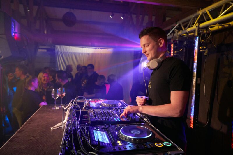 A man stands in a crowded venue controlling music as a 
DJ in this example of music careers.