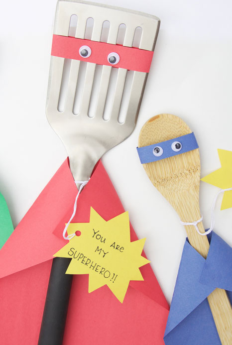A spatula and a spoon are decorated to look like superheroes as an example of father's day gifts for kids.