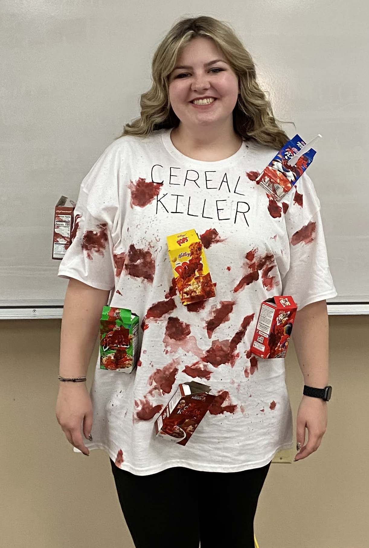 Teacher dressed in a white t-shirt with bloody mini cereal boxes on it, as a cereal killer