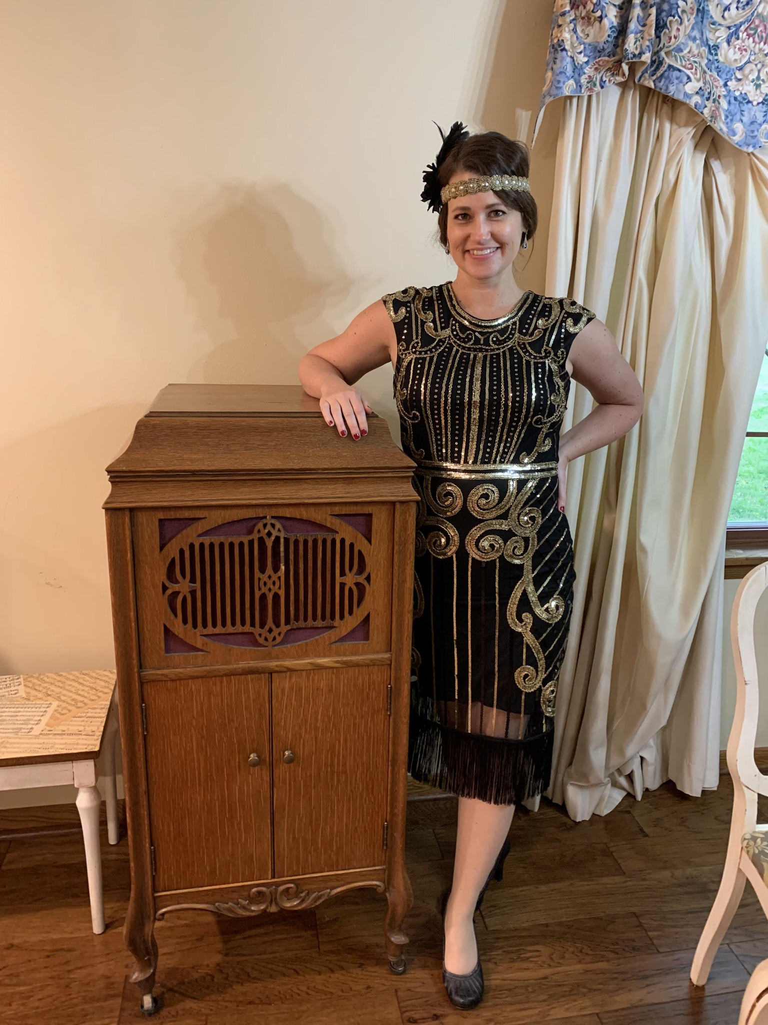 Teacher dressed as a 1920s flapper girl, standing by a vintage radio