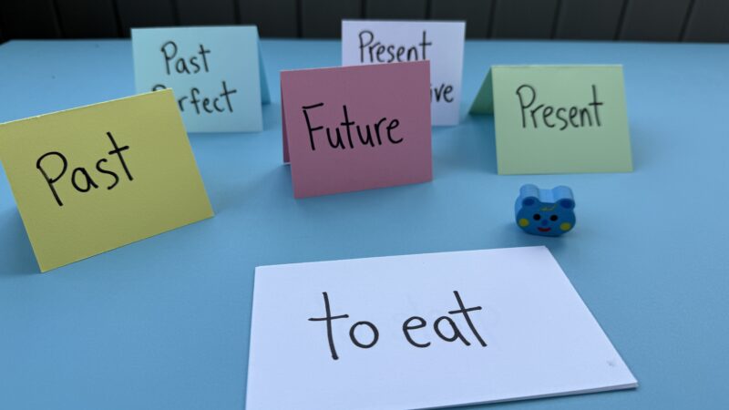 Colorful pieces of paper with verbs written on them propped up like tents Colorful pieces of paper with verbs written on them propped up like tents