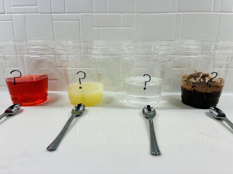 Five Senses Activities four clear cups filled with a mystery liquid with a spoon in front of each cup for students to text and determine their taste